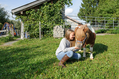Kind mit Pony auf der Koppel beim Reiterhof von Theresia Burger in Waltenhofen-Herzmans am Niedersonthofener See im Oberallgäu