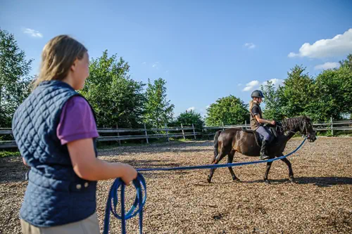 Pony reiten mit Longe in der Manege von Reiterhof von Theresia Burger in Waltenhofen-Herzmans am Niedersonthofener See im Oberallgäu