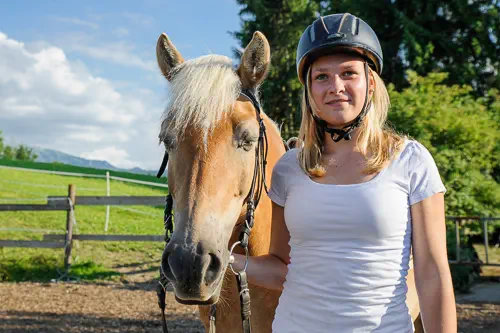 Teenager mit Reithelm und Haflinger in der Manege von Reiterhof von Theresia Burger in Waltenhofen-Herzmans am Niedersonthofener See im Oberallgäu